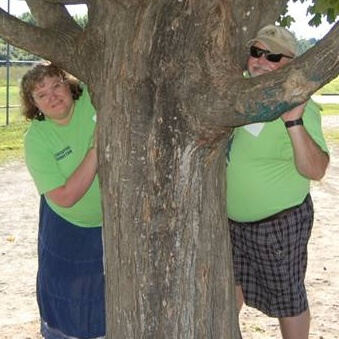 Ron and Sherry Wood hiding behind a tree at Camp Kee-wanee